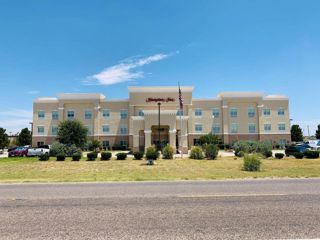 a large building with an american flag in front of it at Hampton Inn Fort Stockton in Fort Stockton