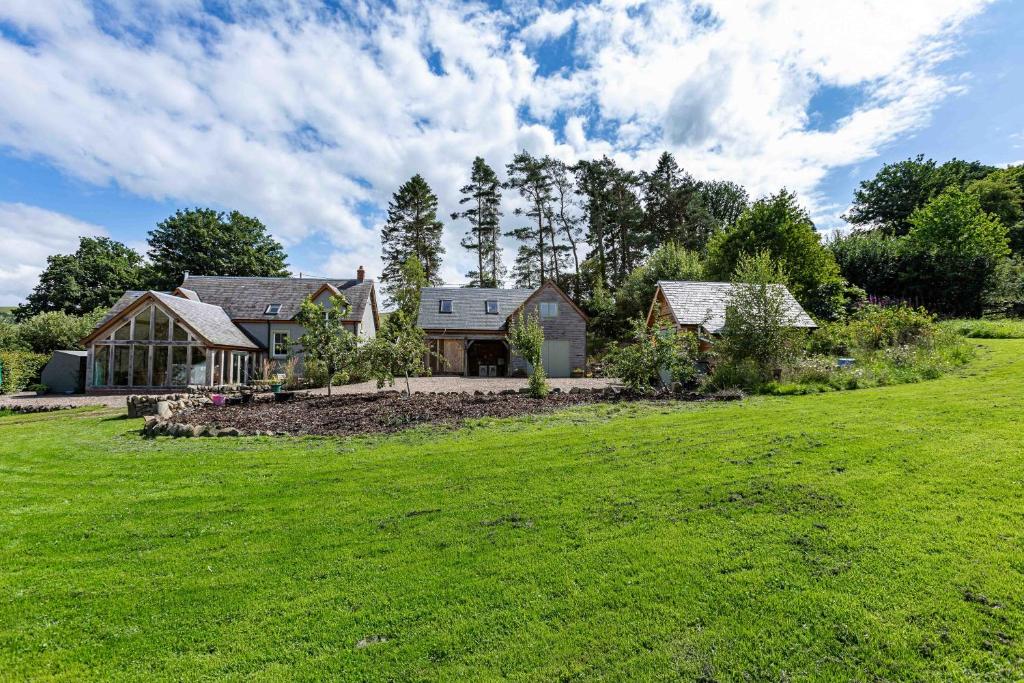 un gran campo verde con una casa en el fondo en The Barn at Dormouse Cottage en Selkirk