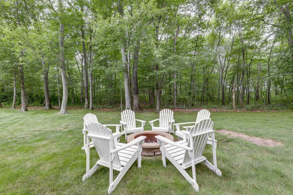 four white chairs around a table in a yard at Spacious Connecticut Home - Deck, Grill and Fire Pit in Mystic