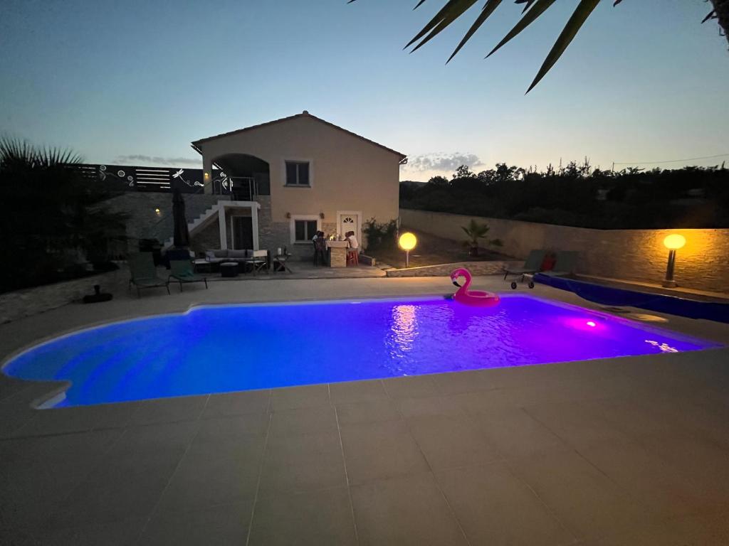 une piscine bleue avec des lumières violettes dans une arrière-cour dans l'établissement Villa Héliopolis, à Ventiseri