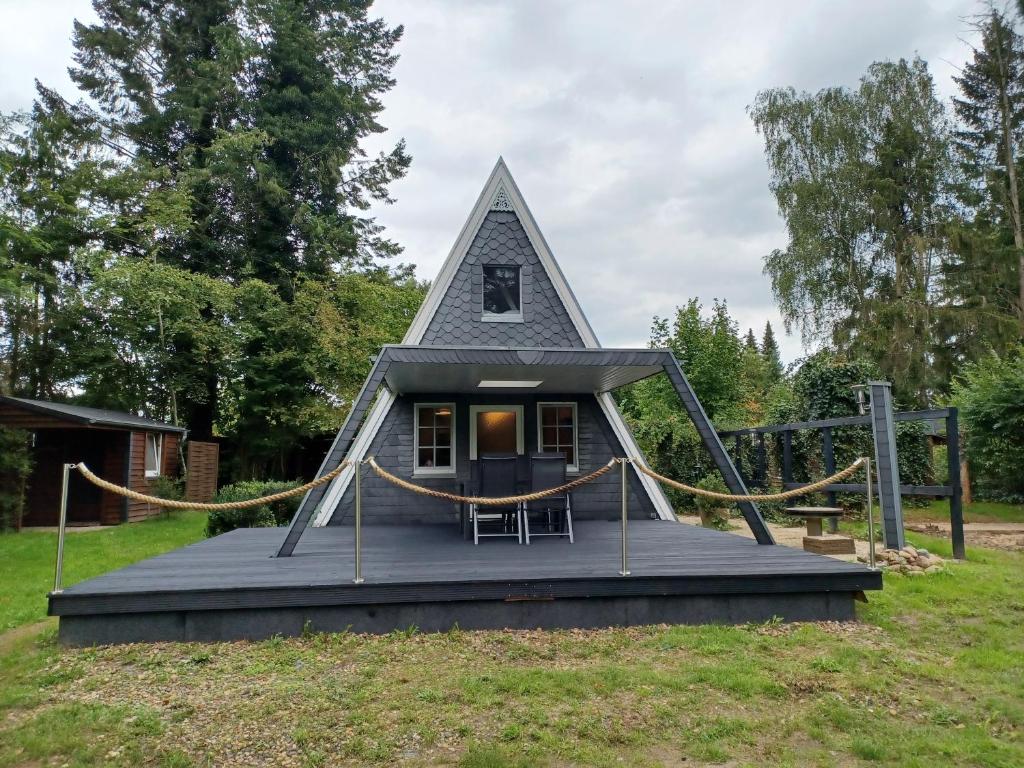 una casa pequeña con un techo triangular en un campo en Ferienhaus Elbliebe - kleine Hunde bis 25 cm willkommen en Dannenberg