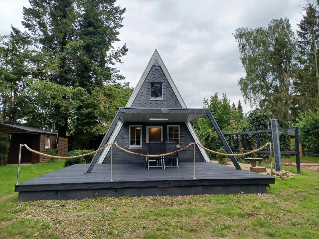 una casa pequeña con un techo triangular en un campo en Ferienhaus Elbliebe - kleine Hunde bis 25 cm willkommen, en Dannenberg
