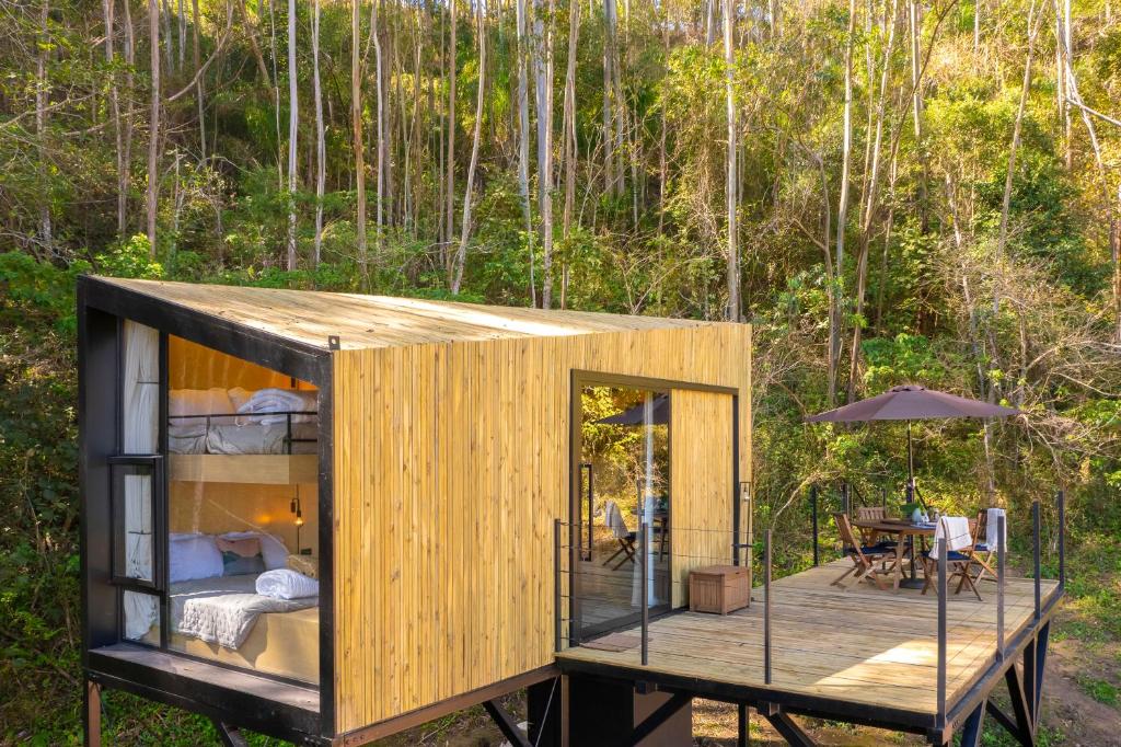 a tiny house on a wooden deck with a bedroom at Altar Ninho in Joanópolis