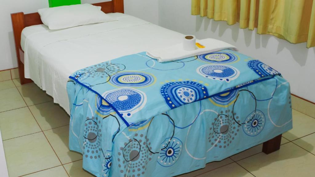 Una cama con una mesa azul y blanca junto a una cama en Hospedaje chanari, en La Merced