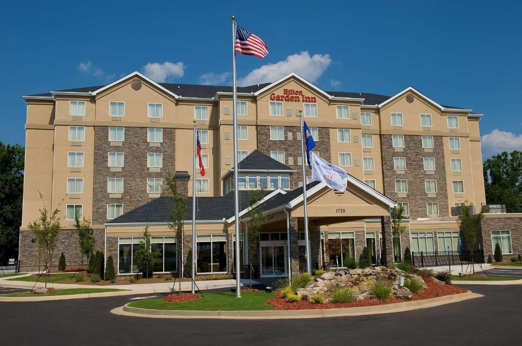 a hotel with two american flags in front of it at Hilton Garden Inn Gainesville in Gainesville