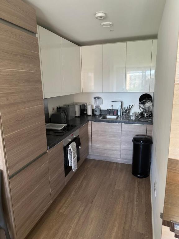 cocina con armarios blancos y suelo de madera en Luxury one bedroom apartment, en Londres
