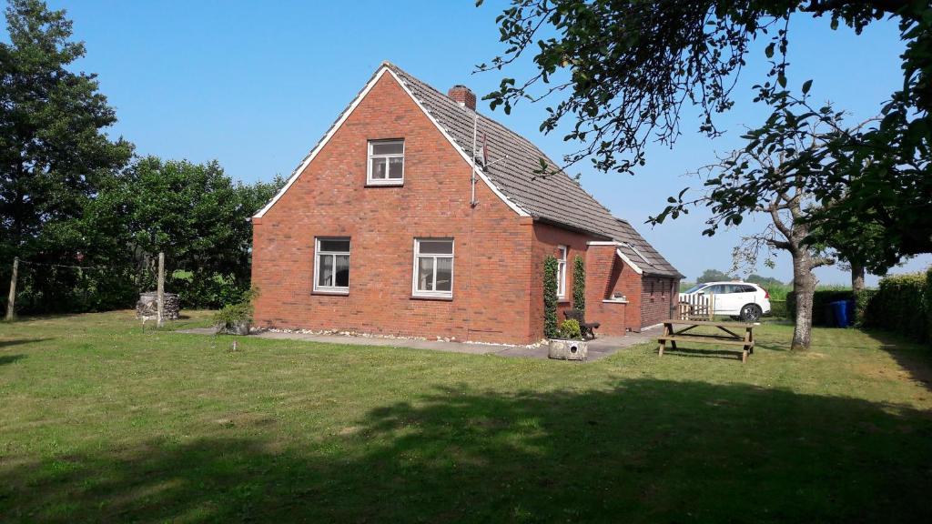 a red brick house with a car parked in front of it at Ferienhaus Nordseebrise in Holtgast