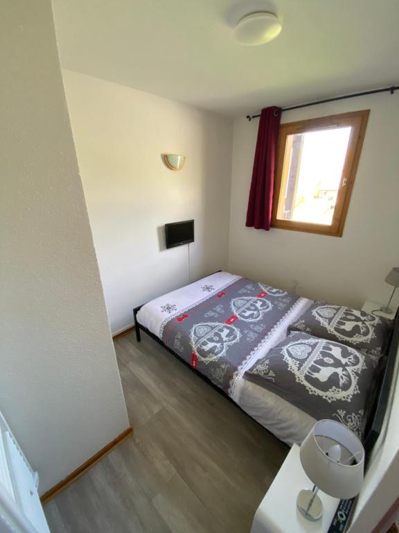 een kleine slaapkamer met een bed en een raam bij Appart SFL 1650m in Saint-François-Longchamp