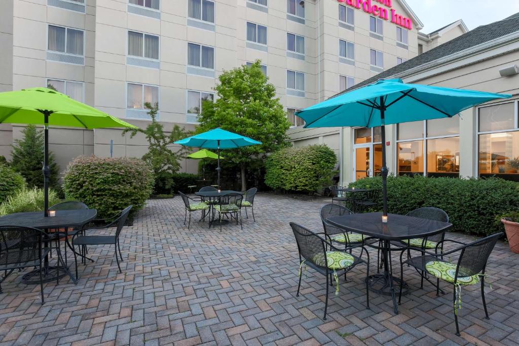 a patio with tables and umbrellas in front of a hotel at Hilton Garden Inn Nanuet in Nanuet