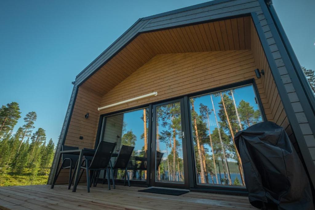 Cabaña con puertas de cristal y sillas en una terraza en Norlight Cottages Ivalo - Aurinko East, en Ivalo