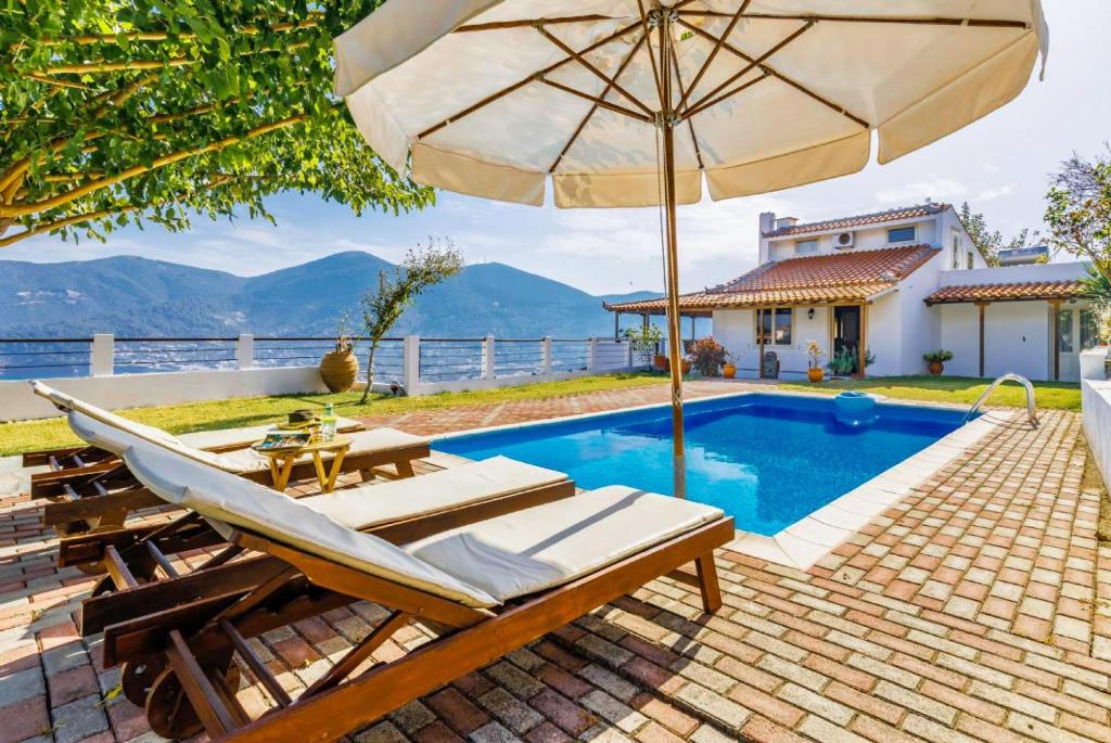 a pool with a table and an umbrella and chairs at Villa Aloupi in Skopelos Town