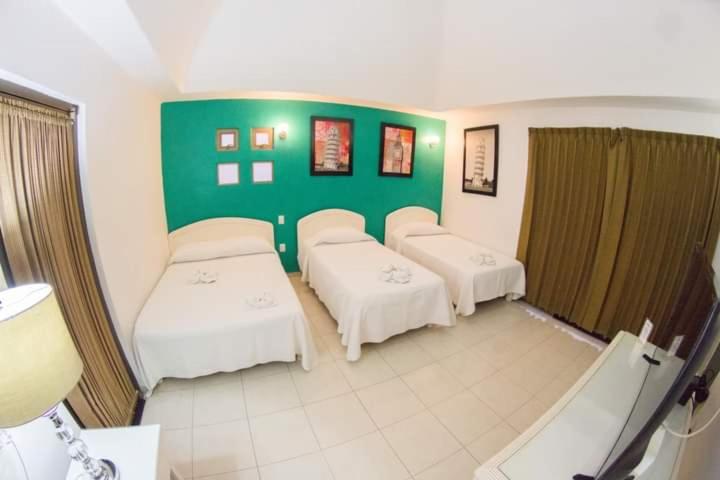 Cette chambre comprend 3 lits et un mur vert. dans l'établissement HOTEL OBREGON, à Iguala de la Independencia