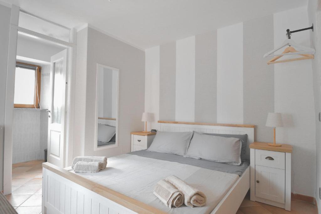 ein weißes Schlafzimmer mit einem Bett mit Handtüchern darauf in der Unterkunft Baceno Room in Baceno