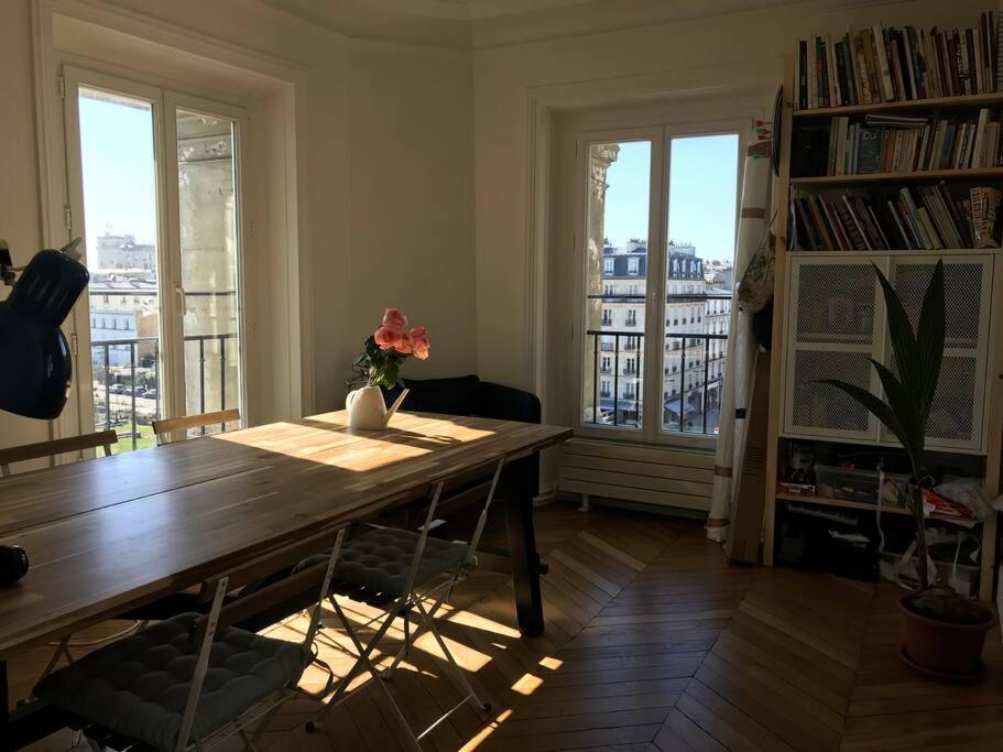 - un salon avec une table en bois et 2 fenêtres dans l'établissement Appartement Haussmanien, lumineux à Paris, à Vincennes