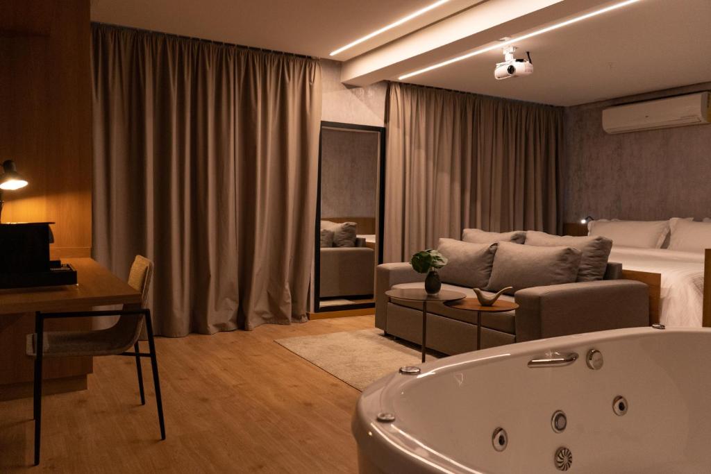 a living room with a bath tub and a bedroom at Intercity Montes Claros in Montes Claros