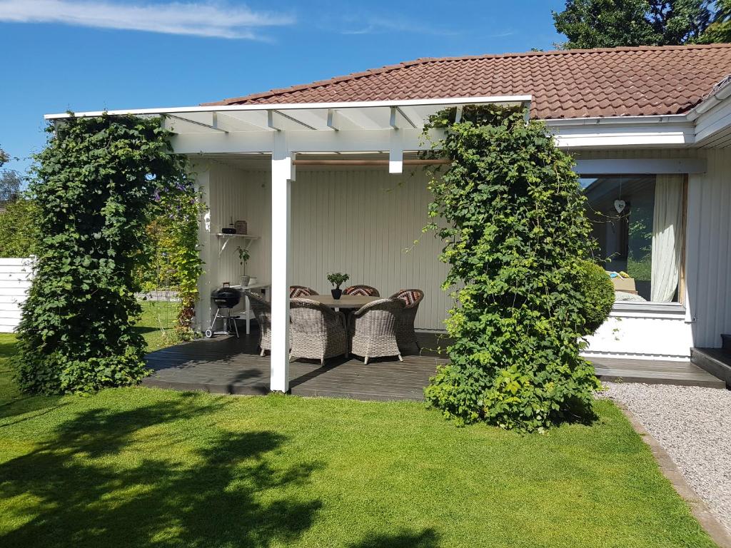 eine Pergola mit einem Tisch und Stühlen auf einer Terrasse in der Unterkunft Holiday home close to forest, lake and skiing in Ulricehamn