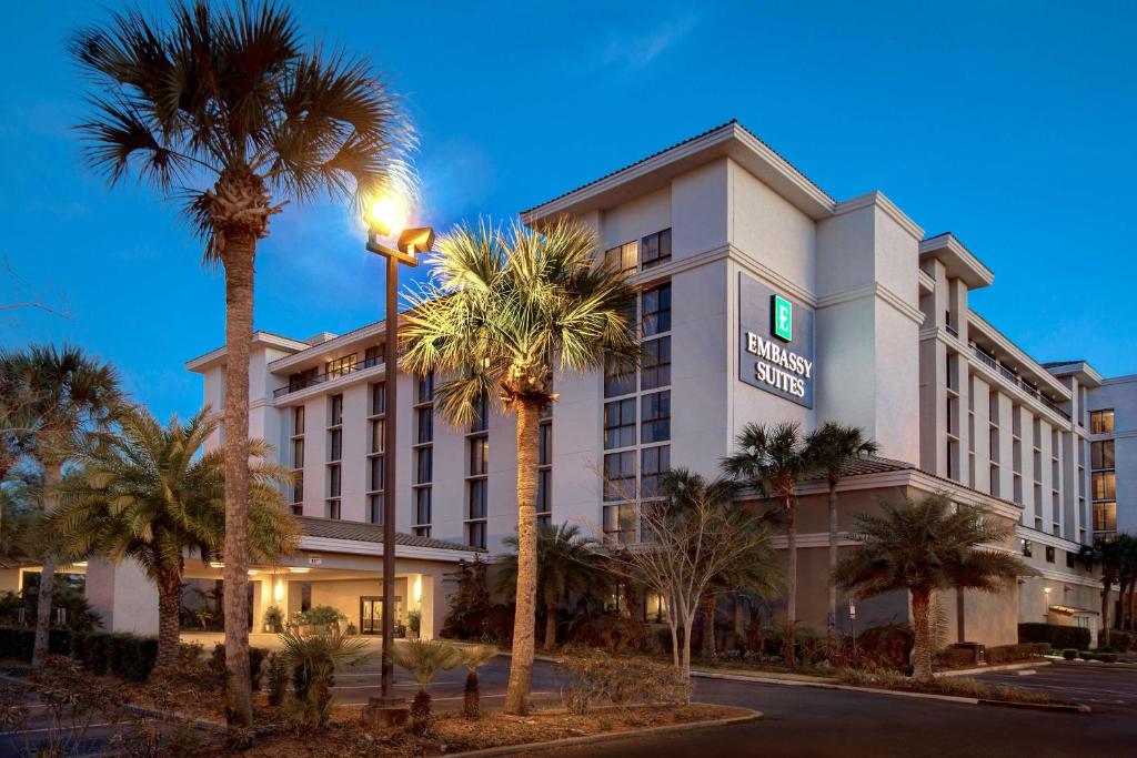 a hotel with palm trees in front of a building at Embassy Suites by Hilton Jacksonville Baymeadows in Jacksonville