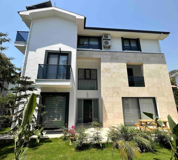 ein großes weißes Haus mit Rasen davor in der Unterkunft Luxurious Villa in the Heart of Göcek in Fethiye