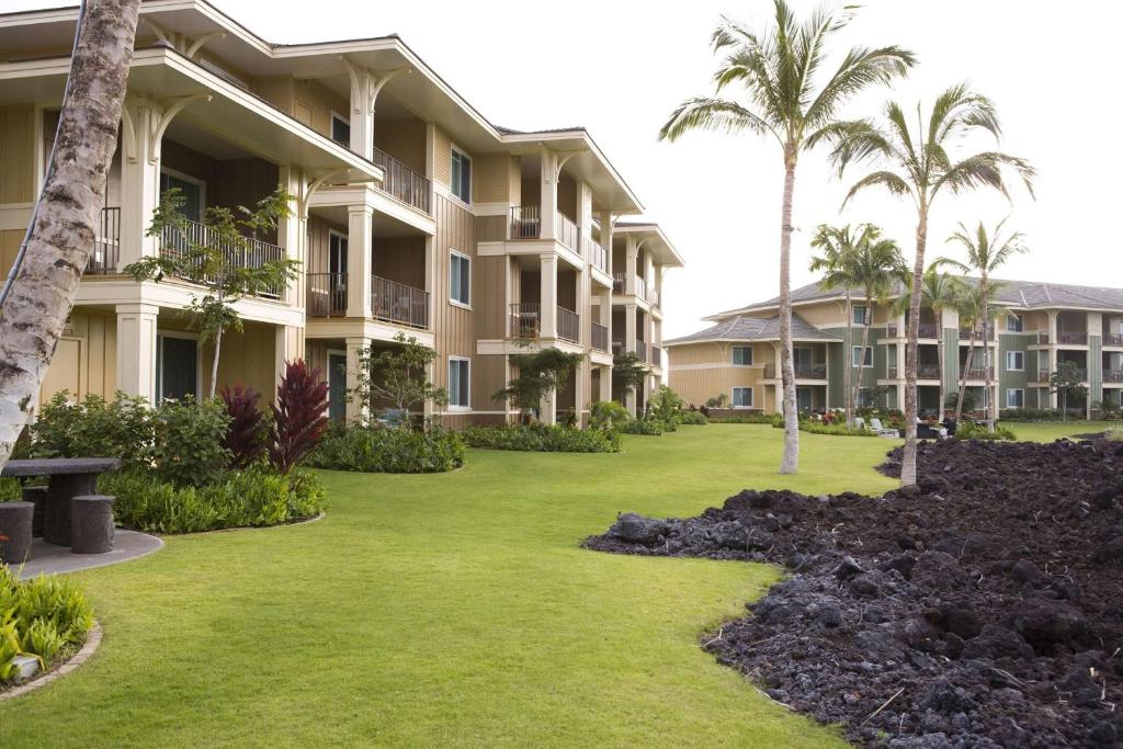 un patio en el complejo con palmeras y apartamentos en condominio en Hilton Grand Vacations Club Kings Land Waikoloa, en Waikoloa