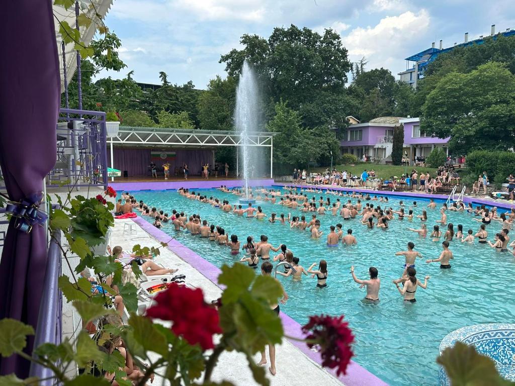a crowd of people in a swimming pool with a fountain at Хотел РИВА in Golden Sands