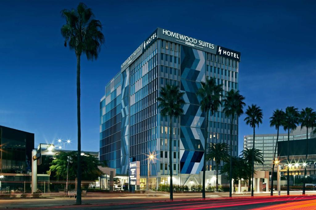 a tall glass building with palm trees in front of it at Homewood Suites By Hilton Los Angeles International Airport in Los Angeles