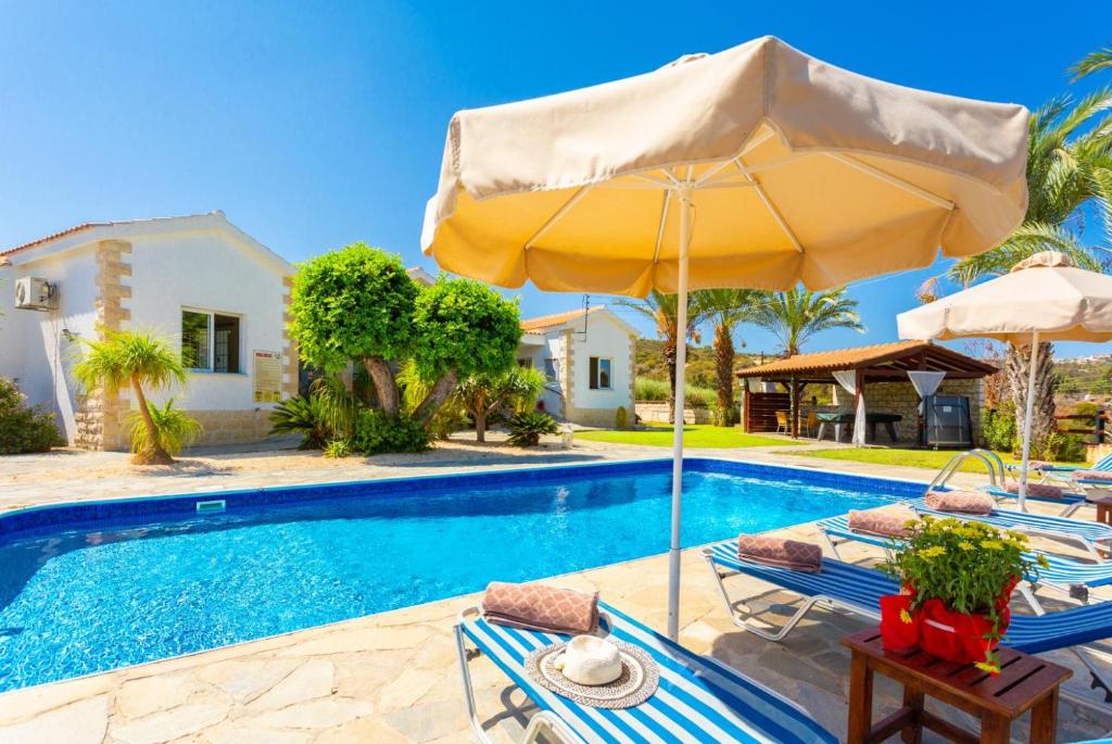 新喬里歐的住宿－Villa Amorosa，一个带椅子和遮阳伞的游泳池以及一间房屋