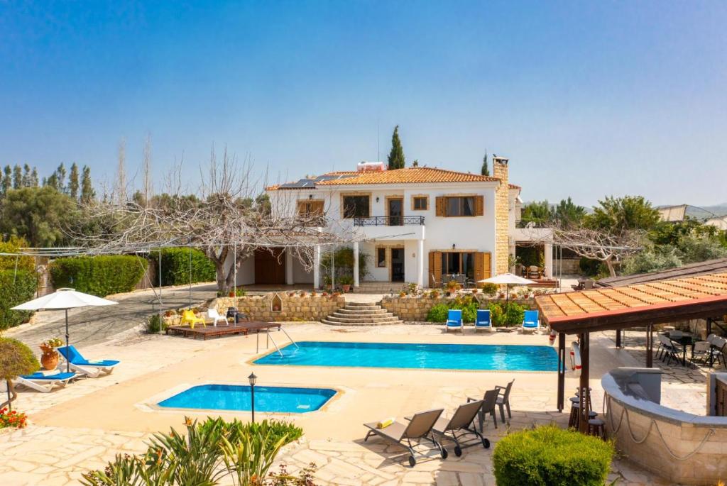 a villa with a swimming pool in front of a house at Villa Xenios Dias in Argaka