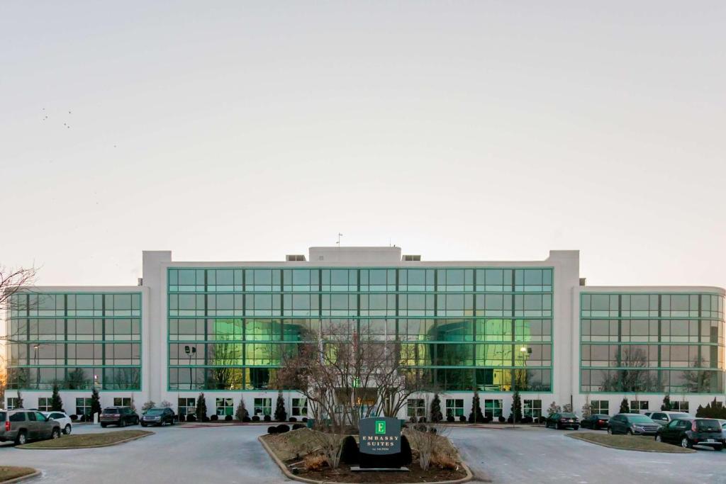 a large glass building with cars parked in a parking lot at Embassy Suites by Hilton Lexington Green in Lexington