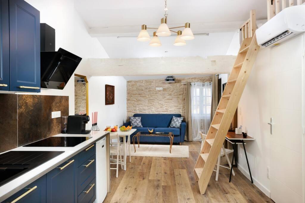 a kitchen and living room with blue cabinets and a ladder at Le Palais d'Aliénor - parking gratuit in Carcassonne