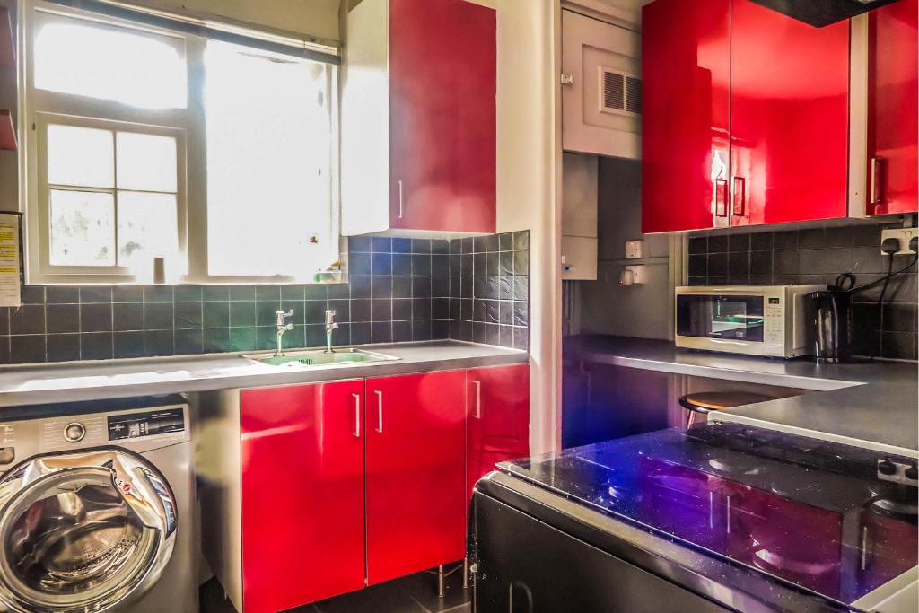 a kitchen with red cabinets and a washing machine at Vintage Room-Only Room in London