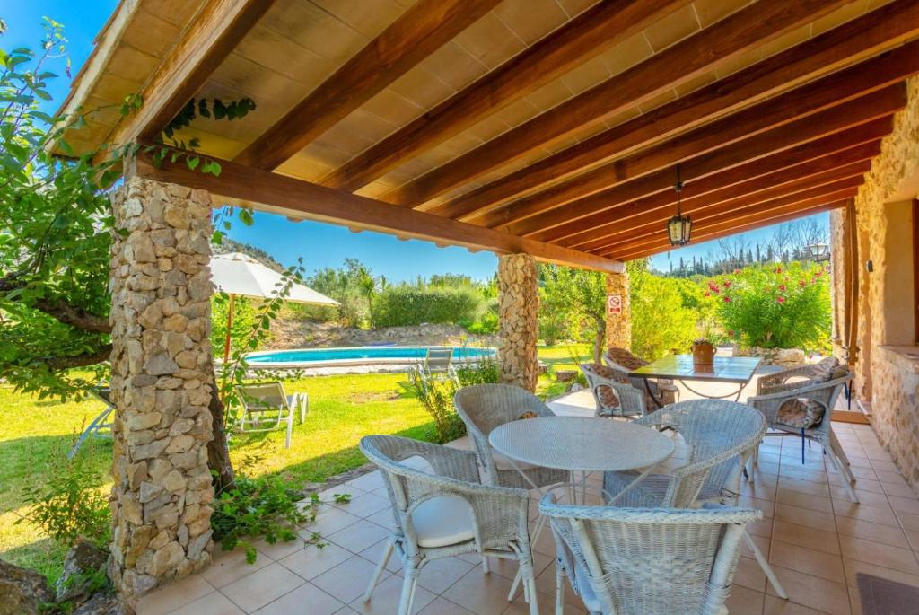 eine Terrasse mit einem Tisch und Stühlen unter einer Pergola in der Unterkunft Can Llobera Private Pool AC WiFi in Pollença