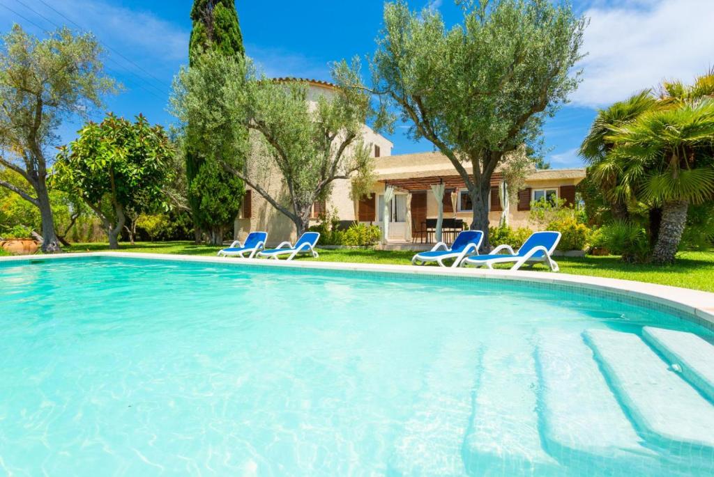 - une piscine avec des chaises et une maison dans l'établissement Villa La Torre, à Alcúdia