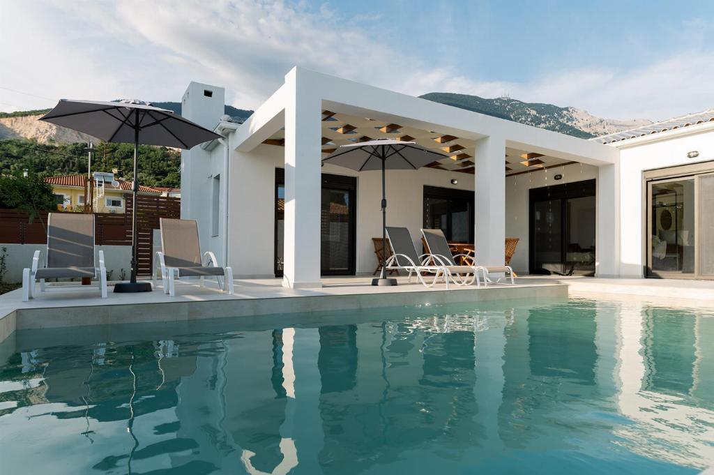 a house with a swimming pool with chairs and umbrellas at Villa Petra in Trapezaki