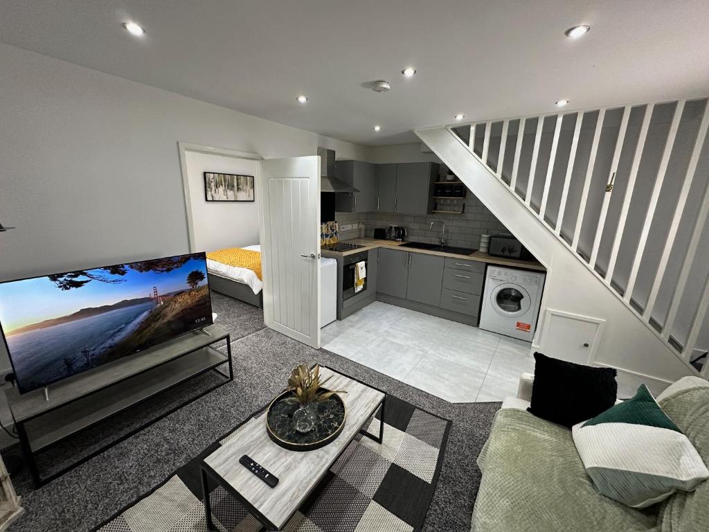 a living room with a couch and a tv and a kitchen at THE GLASS HOUGHTON APARTMENTS in Castleford