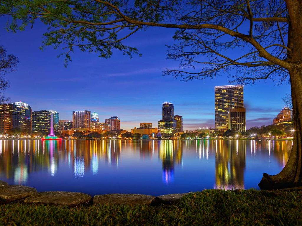 a city skyline reflecting in the water at night at Embassy Suites by Hilton Orlando Downtown in Orlando