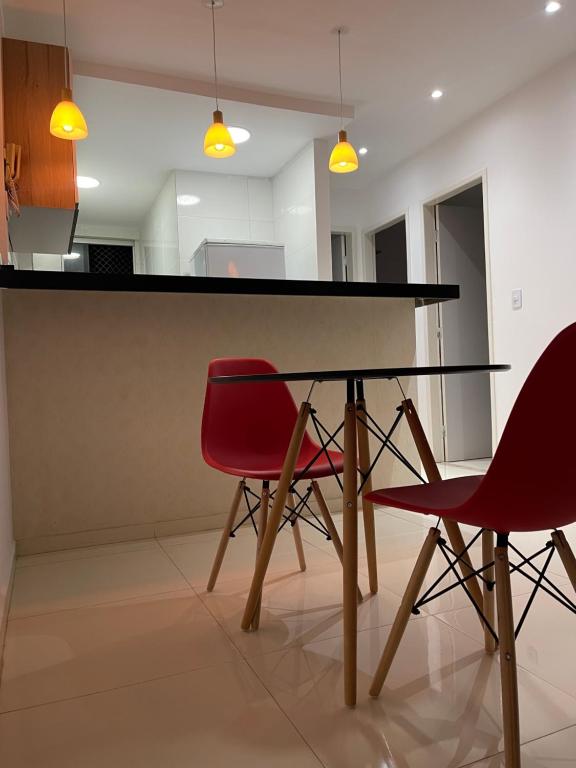 a dining room table with two red chairs at Apto Garagem Wifi Condomínio Piscina Ar-condicionado 2 Quartos in Petrolina