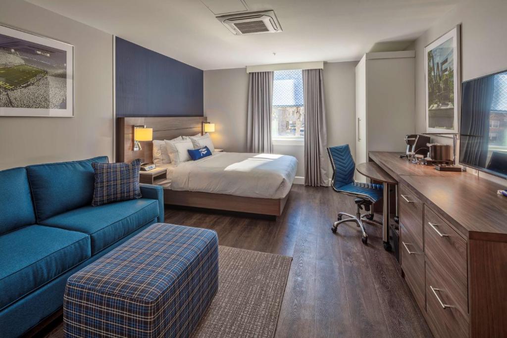 um quarto de hotel com uma cama e um sofá azul em Scholar State College, Tapestry Collection by Hilton em State College