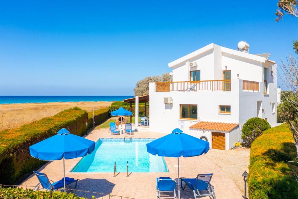 Villa mit einem Pool und blauen Sonnenschirmen in der Unterkunft Blue Bay Villa Thea in Mavroli