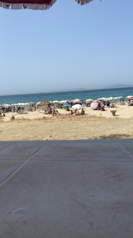 - une plage avec des parasols et des personnes sur la plage dans l'établissement Tanger dar chaoui, à Tanger