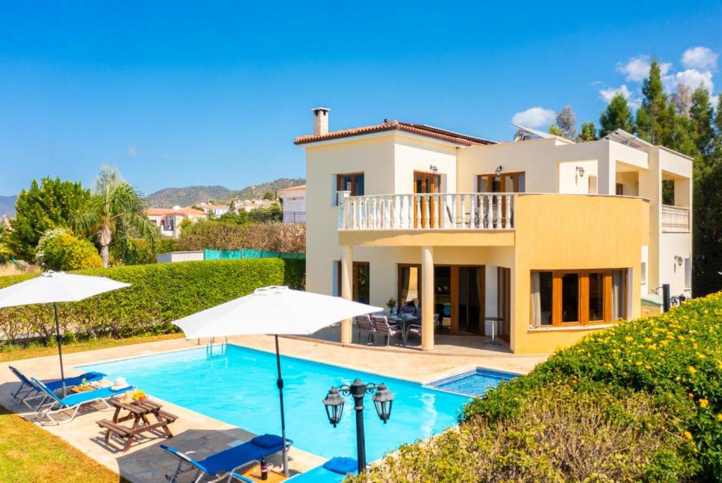 a villa with a swimming pool and a house at Villa Tsikkos Tessera in Argaka