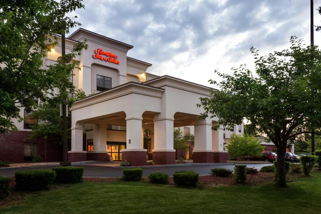 a hotel building with a sign on it at Hampton Inn & Suites by Hilton Manchester Bedford in Bedford