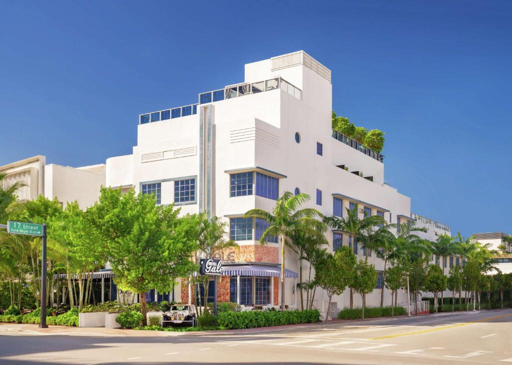 a white building with trees in front of a street at Gale South Beach, Curio Collection By Hilton in Miami Beach