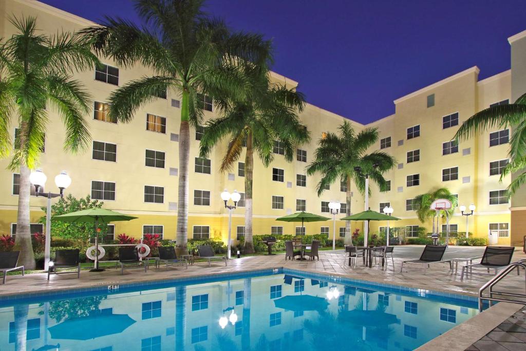 a hotel with a swimming pool in front of a building at Homewood Suites by Hilton Miami - Airport West in Miami