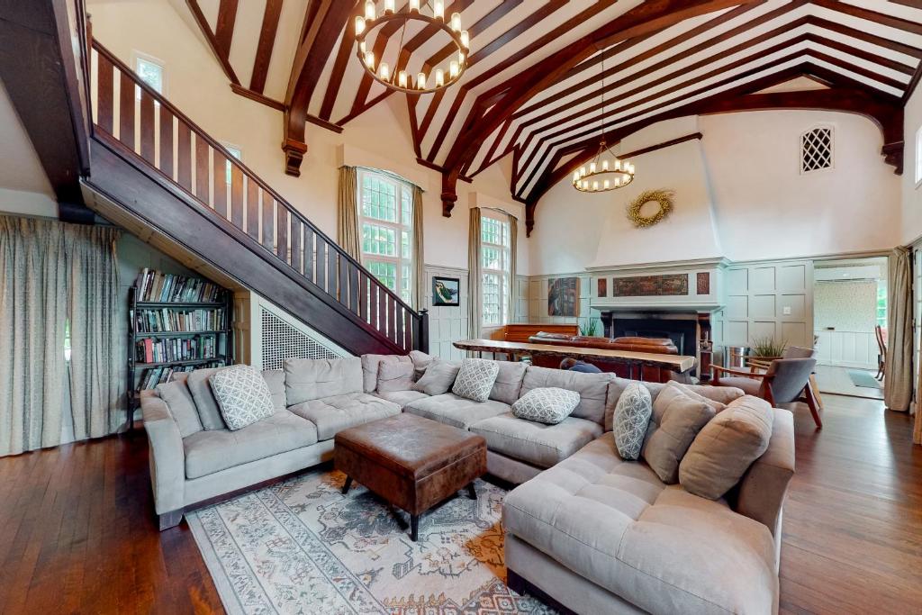 a living room with a large couch and a staircase at Holden Frost House in Franconia