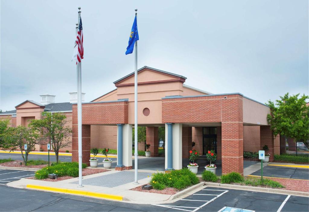 un edificio de ladrillo con dos banderas en un estacionamiento en DoubleTree by Hilton Milwaukee/Brookfield, en Brookfield