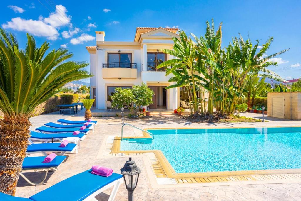a villa with a swimming pool and lounge chairs at Villa Dora in Argaka