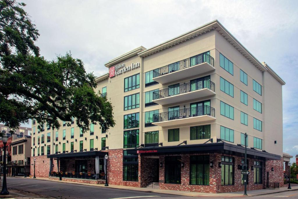 a building on a street with a tree at Hilton Garden Inn Mobile Downtown in Mobile