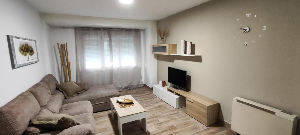 ein Wohnzimmer mit einem Sofa und einem TV in der Unterkunft Piso céntrico in Pobra do Caramiñal