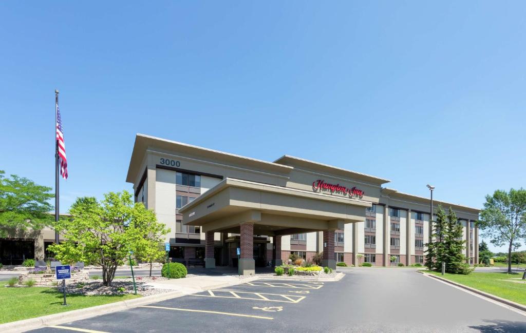 un edificio de hotel con bandera americana en un estacionamiento en Hampton Inn Minneapolis/Eagan en Eagan