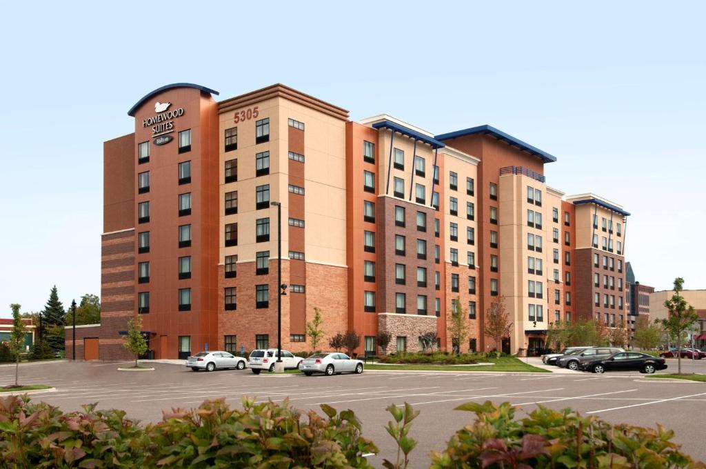 un grande edificio in mattoni con auto parcheggiate in un parcheggio di Homewood Suites by Hilton Minneapolis - Saint Louis Park at West End a Saint Louis Park